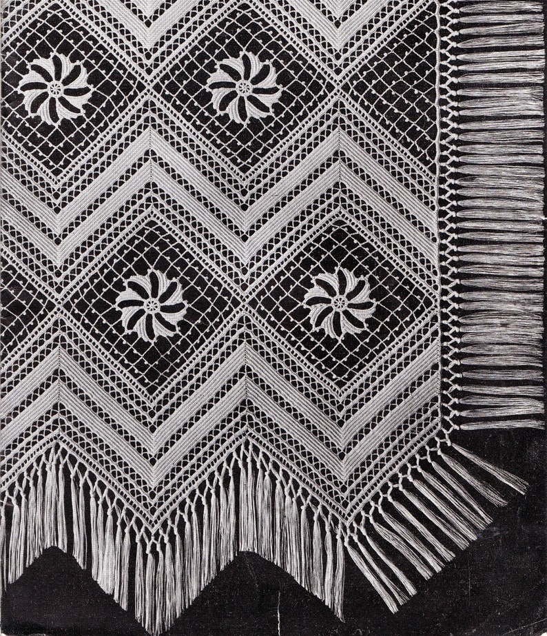 May include: White crocheted lace tablecloth with a geometric pattern and fringe trim. The tablecloth has a black background.