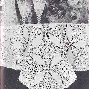 May include: A white crocheted tablecloth with a delicate floral pattern. The tablecloth is laid out on a table with two crystal glasses and a jug.