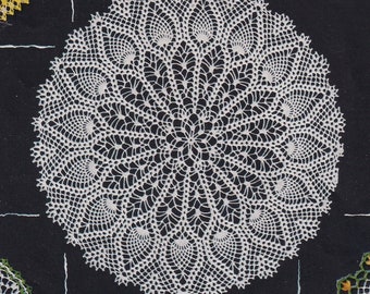 May include: A white crocheted doily with a delicate, intricate design. The doily has a circular shape and features a central motif with radiating patterns.