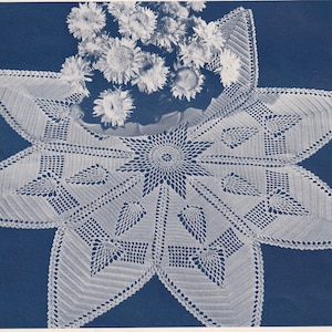 Puede incluir: Mantel de encaje blanco tejido a ganchillo con un diseño de estrella. El mantel está hecho con un patrón delicado y de encaje y tiene un círculo central con un diseño de estrella más pequeño.