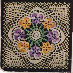 May include: A square, handmade crochet doily featuring a floral design. The center showcases a circular pattern of green and white, surrounded by six pansies in shades of yellow and purple. The doily is framed by a delicate, openwork border.
