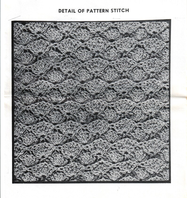 May include: Close-up detail of a crochet stitch pattern. The pattern is made up of small, repeating shapes that create a textured, lacy effect. The stitch is shown in black and white.