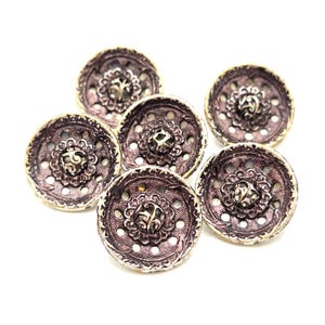May include: Six antique-style buttons with a metallic silver and purple finish. Each button features a detailed floral design in the centre and around the edges. The buttons are round and have a slightly raised profile.
