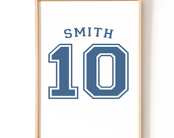 May include: Framed print featuring the name "SMITH" above the number "10" in a blue, collegiate-style font. The print is set against a white background and framed in a light wood.