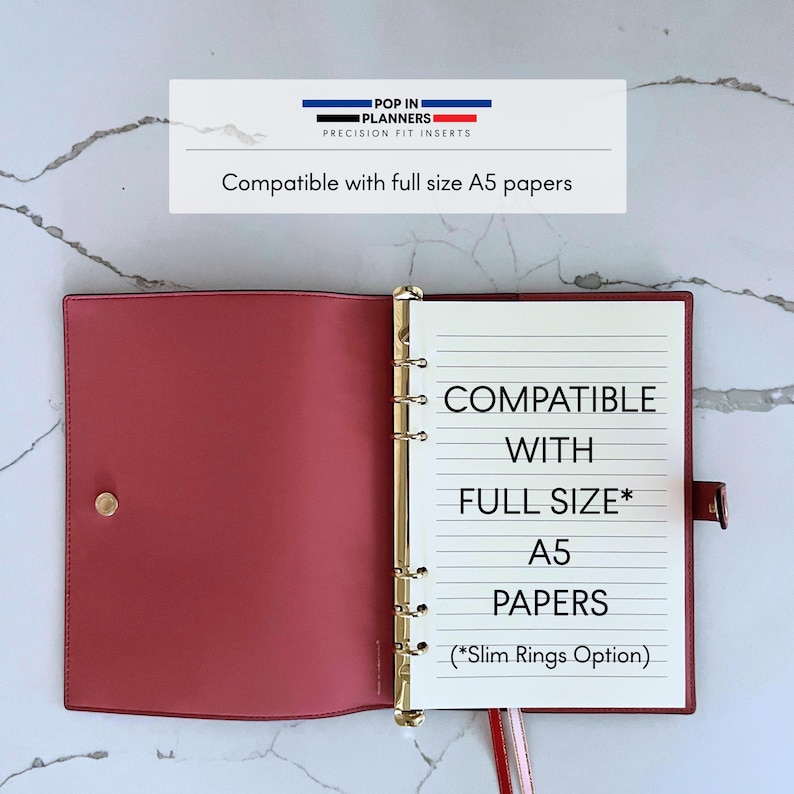 May include: A dusty rose planner binder with a gold six-ring mechanism, featuring a snap closure and white lined paper. The text reads: POP IN PLANNERS PRECISION FIT INSERTS, Compatible with full size A5 papers, COMPATIBLE WITH FULL SIZE* A5 PAPERS (*Slim Rings Option).