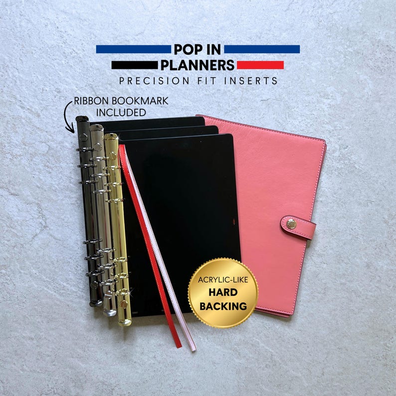 May include: A planner set featuring a coral-colored cover with a snap closure, a black acrylic-like hard backing, and a metal ring mechanism. The text reads POP IN PLANNERS PRECISION FIT INSERTS, RIBBON BOOKMARK INCLUDED, and ACRYLIC-LIKE HARD BACKING.