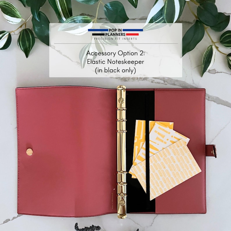 May include: A dusty rose open planner binder with a gold six-ring mechanism and a black elastic band. The text reads: POP IN PLANNERS PRECISION FIT INSERTS Accessory Option 2: Elastic Noteskeeper (in black only). Three yellow patterned cards.
