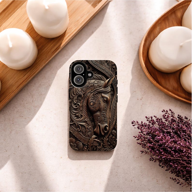 Peut inclure: Une coque de smartphone rectangulaire pr&eacute;sentant un motif en relief brun fonc&eacute; repr&eacute;sentant une t&ecirc;te de cheval entour&eacute;e de volutes et de fleurs complexes. La coque poss&egrave;de une d&eacute;coupe pour double objectif photo et des boutons lat&eacute;raux noirs.