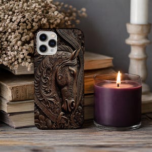 Peut inclure: Une coque de smartphone pr&eacute;sentant une sculpture en relief tridimensionnelle brun fonc&eacute; repr&eacute;sentant une t&ecirc;te de cheval. Le motif comprend des d&eacute;tails floraux et des volutes complexes autour du cheval, avec une d&eacute;coupe pour l'appareil photo.