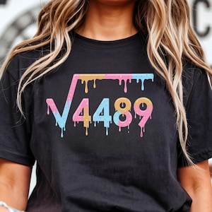Può includere: T-shirt nero con un design colorato a radice quadrata. Il design presenta il numero 4489 in una combinazione di colori pastello a goccia. La maglietta è un classico girocollo.