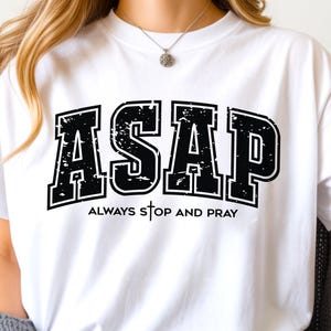 Peut inclure: T-shirt blanc avec l'inscription noire "ASAP" dans une police de style universitaire vieillie. Le texte "Always Stop and Pray" est également présent. C'est un vêtement décontracté pour tous les jours.