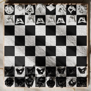 May include: A unique chess set with a wooden frame. The board features black and white squares. The chess pieces are sculpted figures in white and black. The white pieces are figures in various poses. The black pieces are abstract shapes.