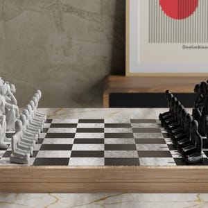 May include: A chess set with white and black pieces arranged on a checkered board. The pieces are stylized human figures. The board is set on a wooden frame. A framed print with a red circle and the word "Deutschland" is in the background.
