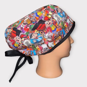 May include: A black scrub hat with a colorful cartoon print featuring characters from the movie The Adventures of Ichabod and Mr. Toad. The hat has black ties.