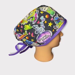 May include: Purple and black surgical scrub hat with a colorful print of potion bottles, stars, and hearts. The text "Sleeping Draught" is printed on the hat.