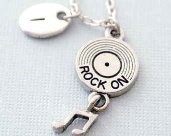 May include: Silver necklace with a charm that looks like a vinyl record with the words "Rock On" on it. The charm is attached to a silver music note charm.
