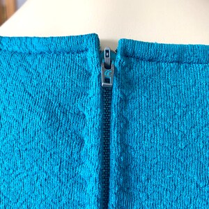 May include: A teal blue dress with a zipper closure in the back.