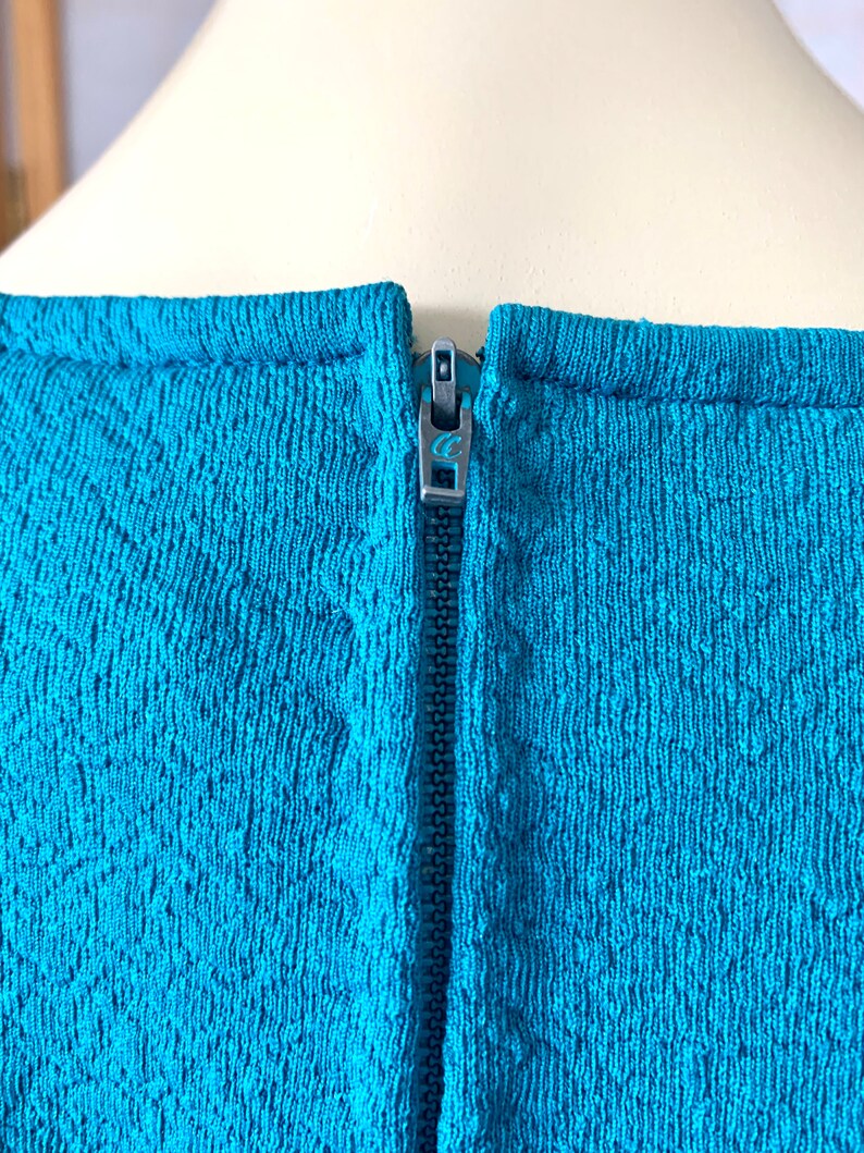 May include: A teal blue dress with a zipper closure in the back.