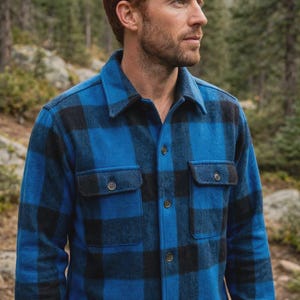 May include: A long-sleeve button-up shirt featuring a bold blue and black buffalo plaid pattern. The shirt is constructed with a classic collar, a front button placket, and two chest pockets with buttoned flaps, showcasing a textured fabric finish.