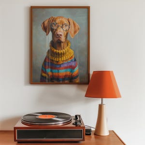 Puede incluir: Un retrato enmarcado de un perro con gafas redondas y un su&eacute;ter a rayas de colores. El retrato cuelga sobre un tocadiscos vintage y una l&aacute;mpara naranja moderna.