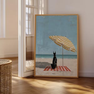 May include: A framed art print depicts a black dog sitting on a red and white striped beach towel under a yellow and white striped umbrella. The artwork is set on a sandy beach with a blue ocean and sky.