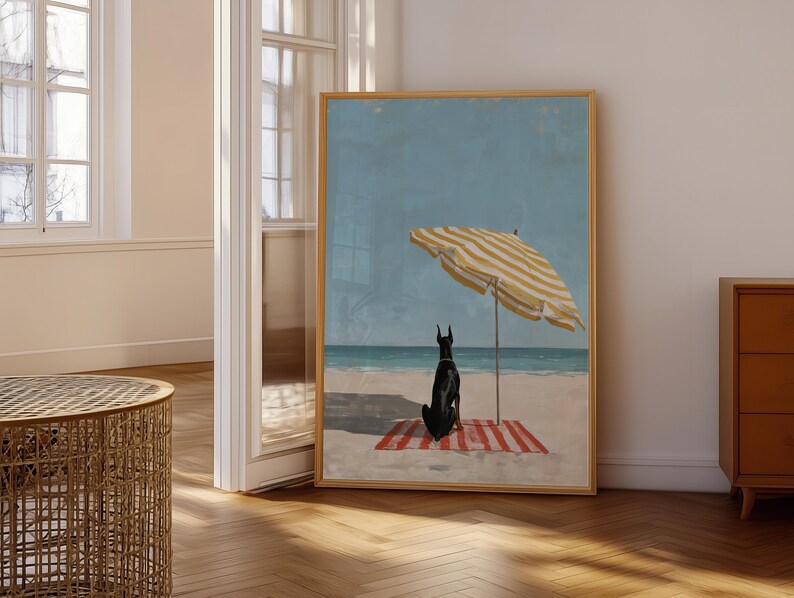 May include: A framed art print depicts a black dog sitting on a red and white striped beach towel under a yellow and white striped umbrella. The artwork is set on a sandy beach with a blue ocean and sky.