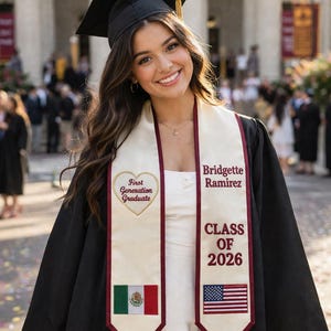 May include: A graduate in a black cap and gown, smiling at the camera. The graduate wears a white sash with the text "First Generation Graduate" and "Class of 2026." The sash features the Mexican and American flags. The background is a building.