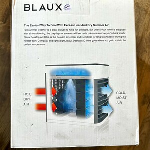 Puede incluir: Una caja blanca con el nombre de la marca "BLAUX" en letras negras. La caja presenta un diagrama de un enfriador de aire y humidificador de escritorio, con etiquetas que indican "AIRE CALIENTE Y SECO" y "AIRE FR&Iacute;O Y H&Uacute;MEDO".