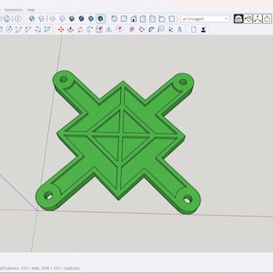 May include: A green, geometric monitor mount design with a symmetrical, cross-like shape. The mount features four extended arms with circular holes at the ends for mounting. The central portion has a diamond-shaped pattern.