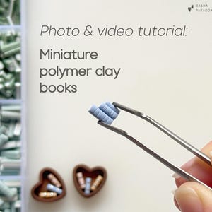 Puede incluir: Primer plano de libros de arcilla polimérica en miniatura sostenidos por pinzas. Los libros son de color azul claro y se sostienen frente a un fondo blanco. La imagen también incluye el texto "Photo & video tutorial: Miniature polymer clay books."