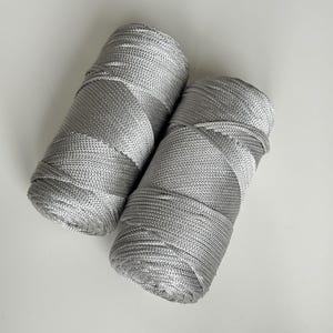 May include: Two spools of silver metallic thread. The thread is wound tightly and has a shiny finish.