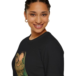May include: Black t-shirt with a vibrant illustration of a woman in traditional Indian dress. The design showcases a woman in a green and gold outfit, adorned with detailed patterns. The t-shirt is made from a soft, comfortable fabric.