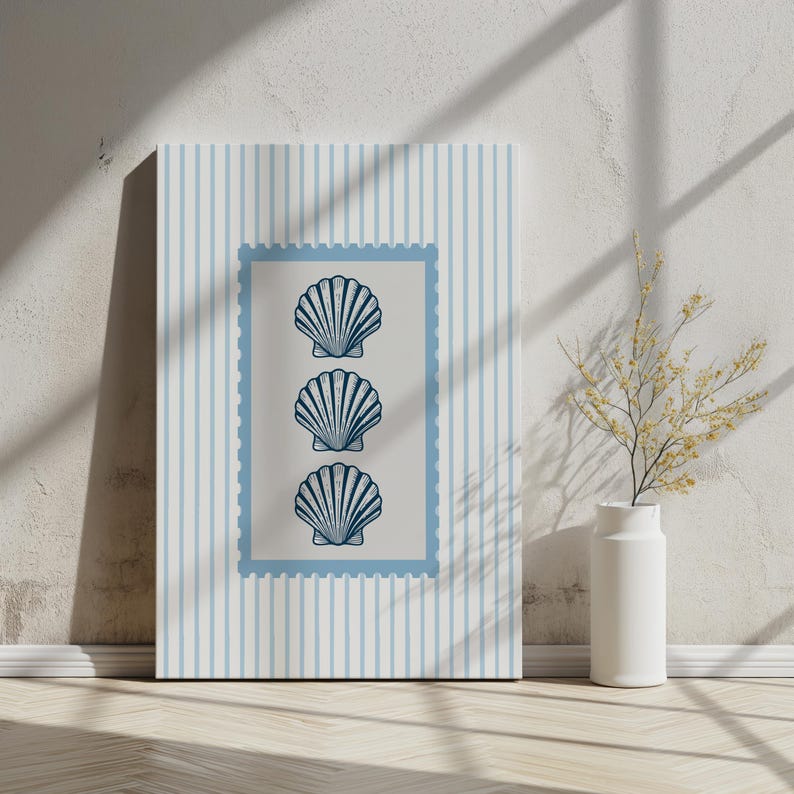 May include: A framed canvas art print featuring three stylized seashell illustrations in a vertical arrangement. The seashells are navy blue on a light beige background, framed by a light blue border. The background has light blue vertical stripes.