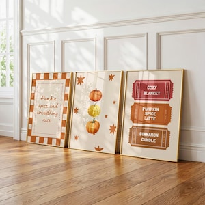 May include: Three framed wall art prints featuring autumn themes. The left print has a checkered border and the text Pumpkin spice and everything nice. The centre print shows three pumpkins and stars. The right print displays three ticket-style graphics.