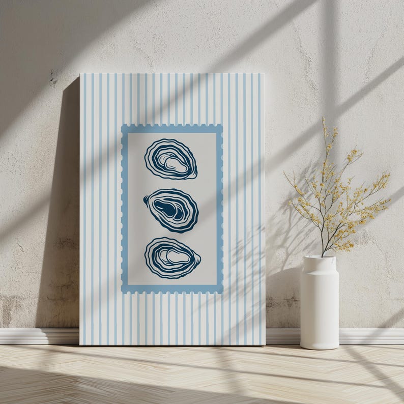 May include: A canvas print featuring three stylized oyster illustrations in a blue frame. The background has vertical blue stripes. The artwork is displayed on a wooden floor, leaning against a white wall.