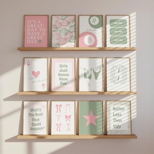 Puede incluir: Una colección de doce láminas de arte mural rectangulares dispuestas en tres estantes de madera. Los diseños presentan varios motivos en rosa y verde, incluyendo textos como 'It's a great day to have a great day', 'Girls just wanna have fun' y 'Better late than ugly', junto a ilustraciones de labios, bolas de billar, entradas, cartas, bikinis, lazos y estrellas.