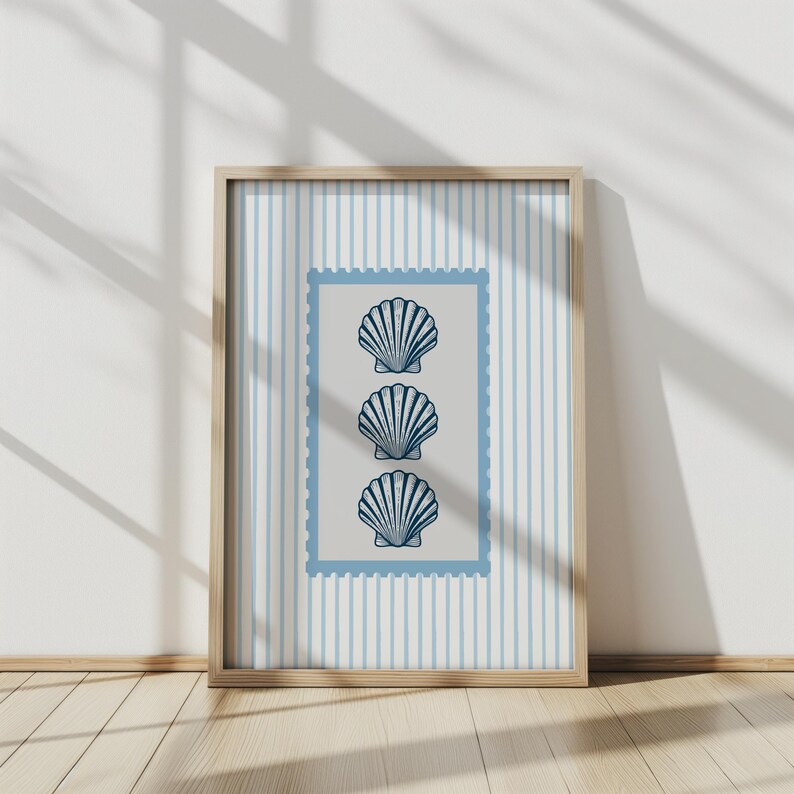 May include: A framed print featuring three stylized blue seashell illustrations on a light gray background within a blue postage stamp border. The background has vertical light blue stripes. The frame is made of light-colored wood.