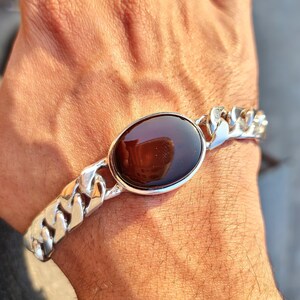 May include: A silver chain bracelet with a large oval-shaped brown gemstone set in a silver bezel.