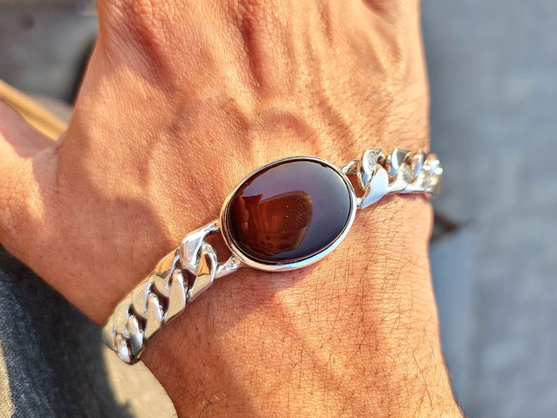 May include: A silver chain bracelet with a large oval-shaped brown gemstone set in a silver bezel.