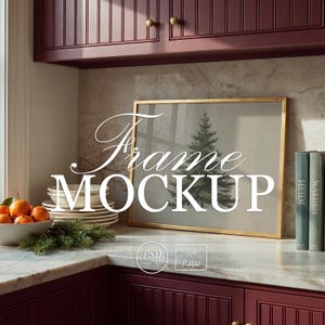 May include: A horizontal gold-toned picture frame containing a print of a pine tree, positioned on a marble countertop. The frame is displayed in a kitchen with dark red cabinets, a bowl of oranges, and two books labeled Heidi and Walden.