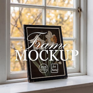 May include: A black framed art print with a floral design, leaning against a white window. The artwork features white and orange daffodils on a dark background. The words "Frame MOCKUP" are displayed on the image, along with "PSD Smart Object" and "3:4 Ratio".