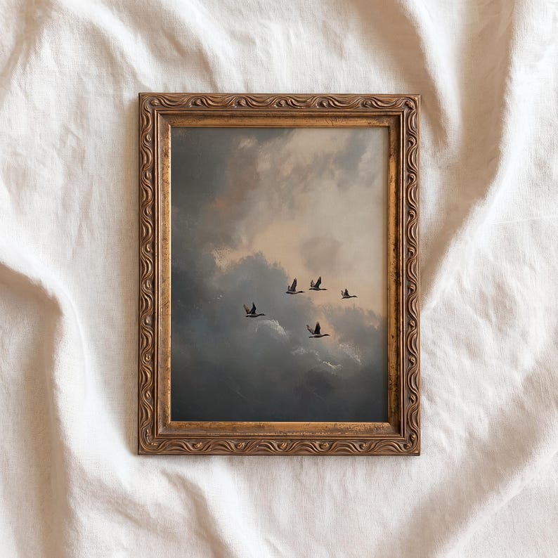 May include: A framed art print featuring a dramatic cloudy sky with a flock of birds in flight. The artwork is set within an ornate, gold-colored frame. The overall aesthetic is reminiscent of a vintage painting.