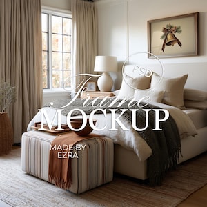 May include: A bedroom interior with a bed, ottoman, and framed artwork. The bed has white linens, pillows, and a gray blanket. The ottoman is striped with a brown throw. The artwork features a bell with a bow.