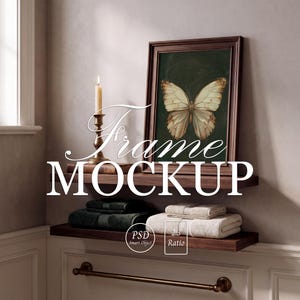 May include: A framed butterfly print, a lit candle in a brass holder, and folded towels are displayed on a dark wood shelf. The words "Frame MOCKUP" are displayed in a decorative font. A metal towel rack is mounted below the shelf.