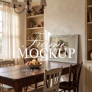 May include: A dining room setting with a wooden table, chairs, and a framed picture. The picture displays a Christmas bell design. The text "Frame Mockup" and "Made by Ezra" are visible. A bowl of fruit and a lit candle are on the table.
