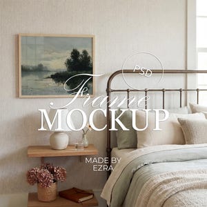 May include: A framed landscape painting hangs above a bed with a metal headboard. The bed is made with light-colored bedding and pillows. A nightstand with a lamp, vase, and flowers is visible. The text "Frame Mockup" is displayed.