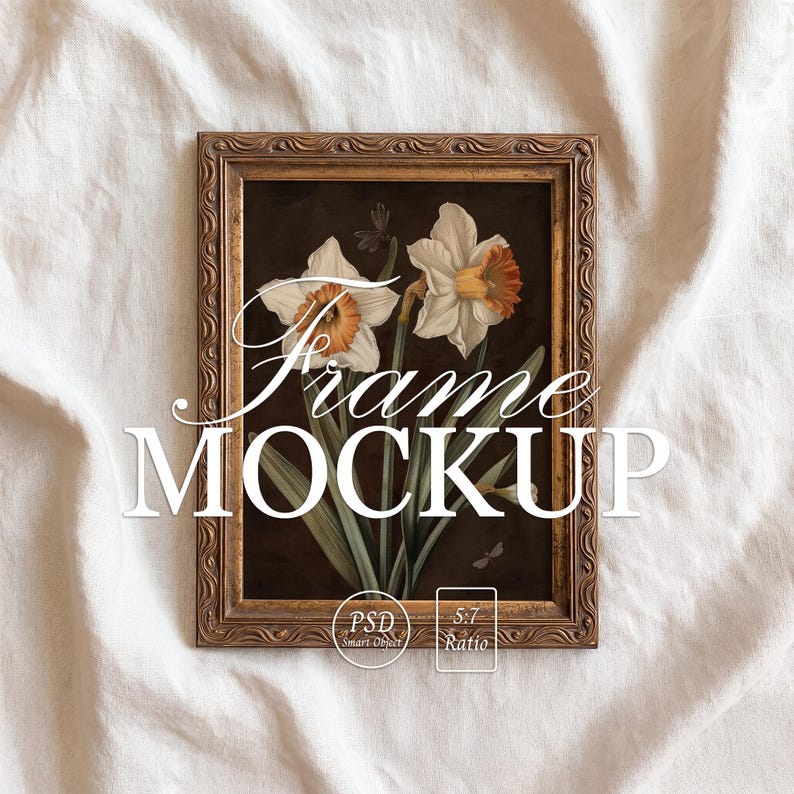 May include: A framed floral art print featuring white and orange daffodils against a dark background. The frame is a detailed gold color, and the text "Frame MOCKUP" is displayed across the image. The image is set against a white fabric backdrop.
