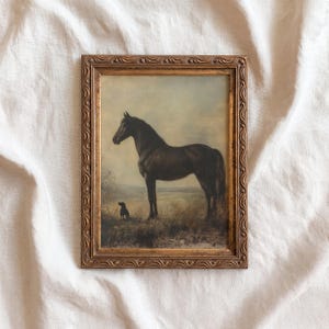 May include: A framed vintage painting depicts a dark brown horse standing in a field with a small black dog. The painting has a gold-colored ornate frame. The background shows a landscape with a light blue sky.