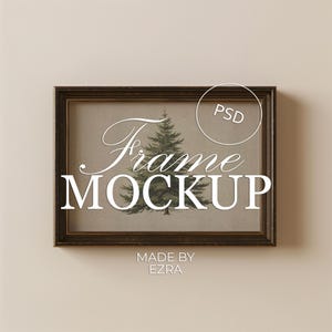 May include: A framed art print mockup featuring a detailed illustration of a green pine tree. The frame is dark brown with a distressed finish. The words "Frame MOCKUP" are displayed in white script and block letters. The text "MADE BY EZRA" is also visible.