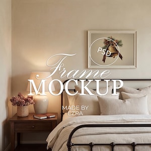 May include: A bedroom scene featuring a bed with a black metal frame, adorned with neutral-toned bedding and pillows. A framed picture of a bell with a bow hangs above the bed. A nightstand with a lamp and decorative items is visible.